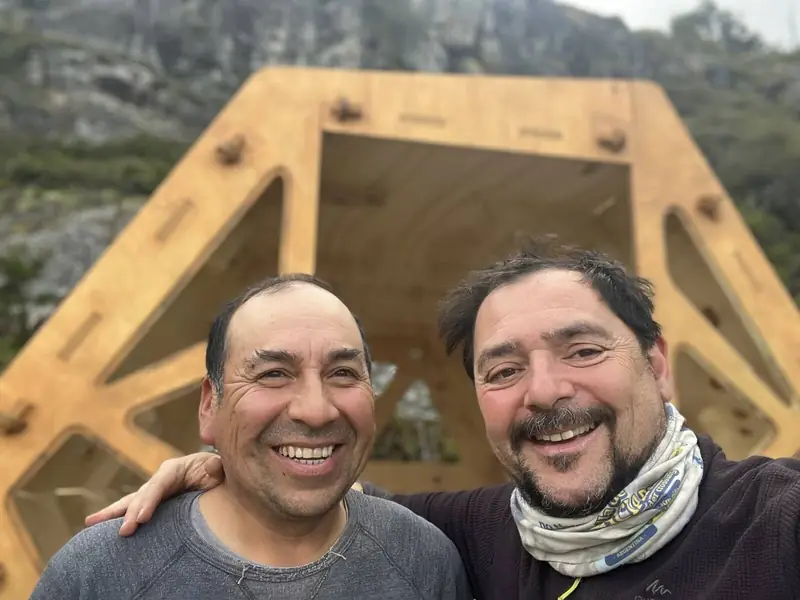 Ricardo y Javi, sonriendo frente a un refugio recién armado