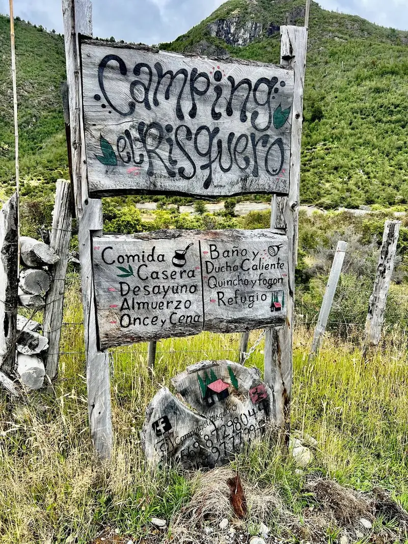 El letrero de El Risquero: comida casera, desayuno, almuerzo, once y cena; baño y ducha caliente; quincho y fogón; refugio