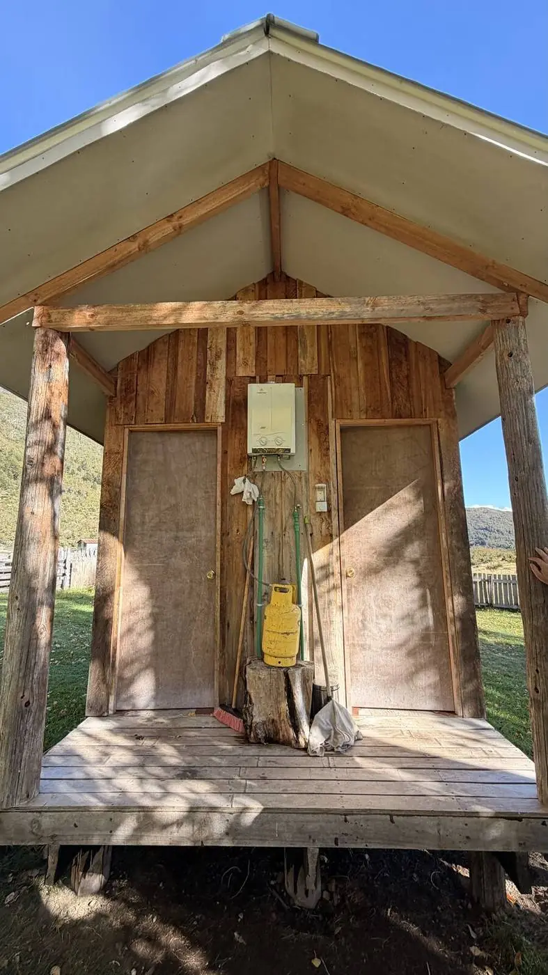 Una construcción de madera con alero, junto al pasto