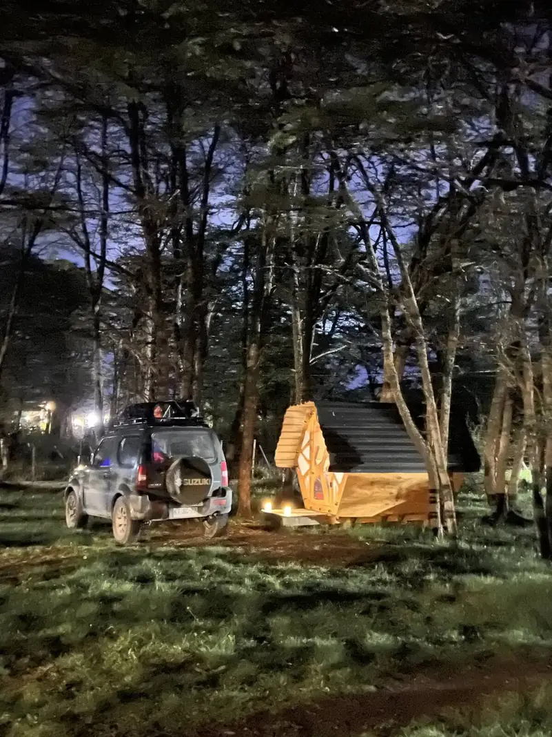Un refugio iluminado de noche, con un auto al lado