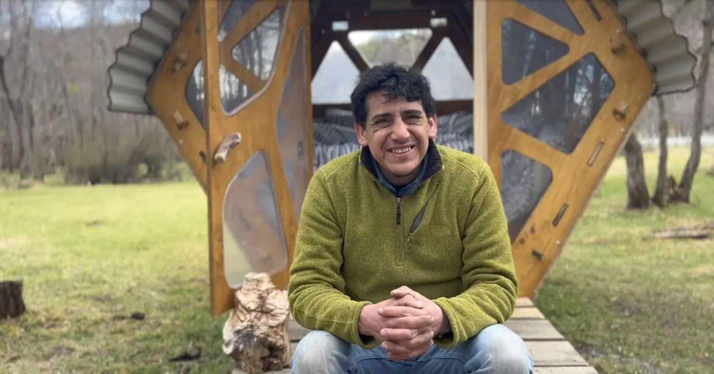 Pachi sentado frente a un refugio, en el bosque
